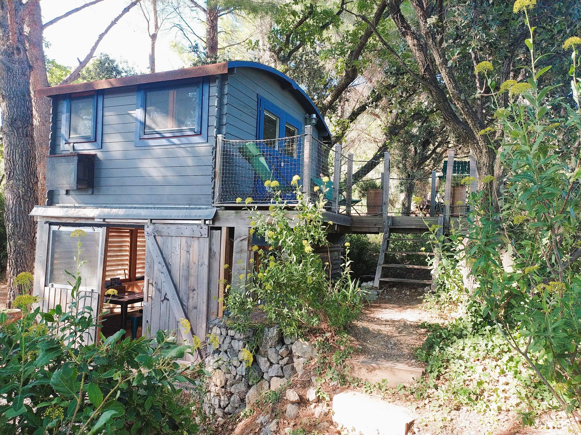 Une cabane perchée au milieu de la nature. Coin repas en bas, terrasse et chambre à l'étage.