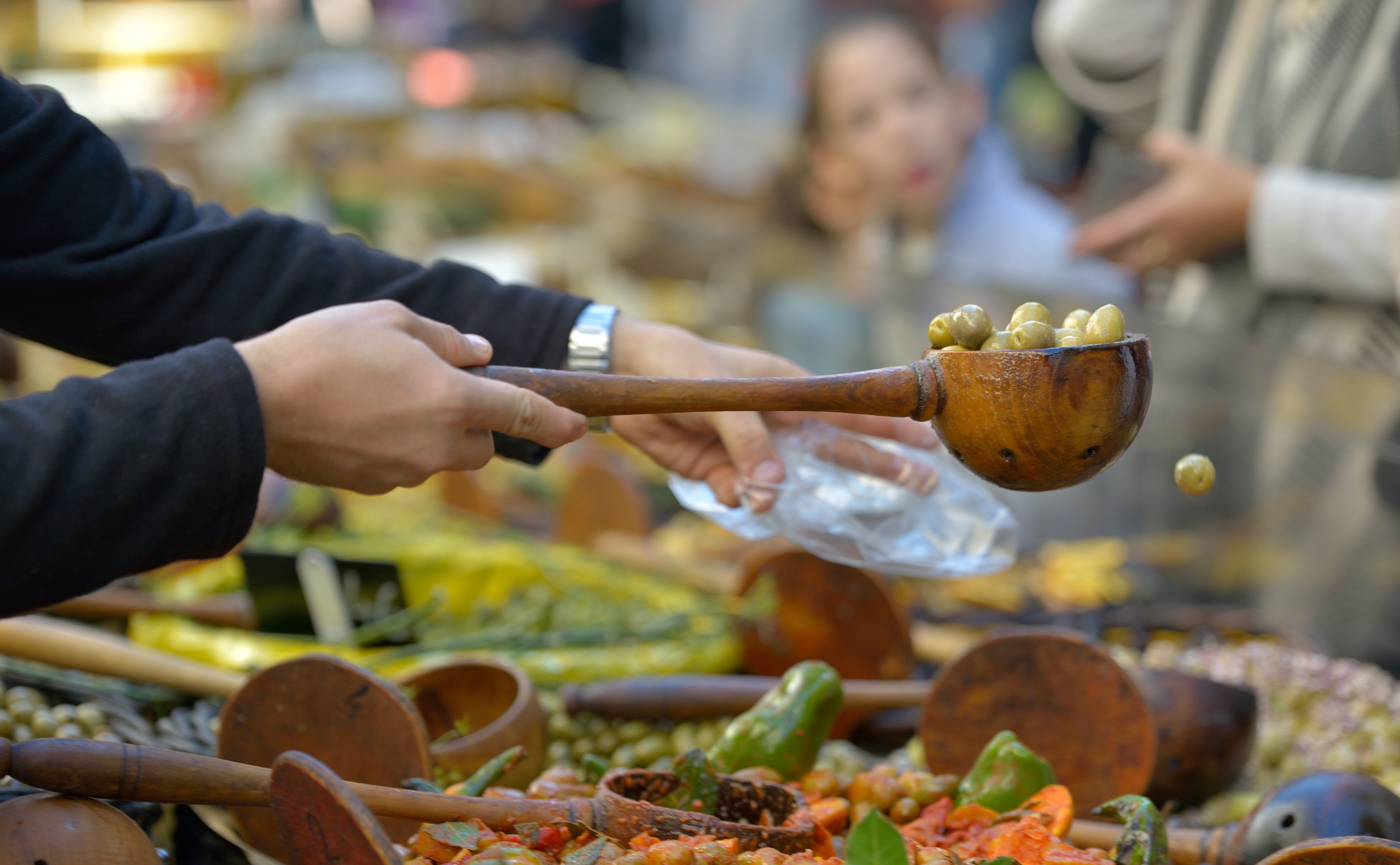 Vendeur préparant un sachet d'olives sur le marché